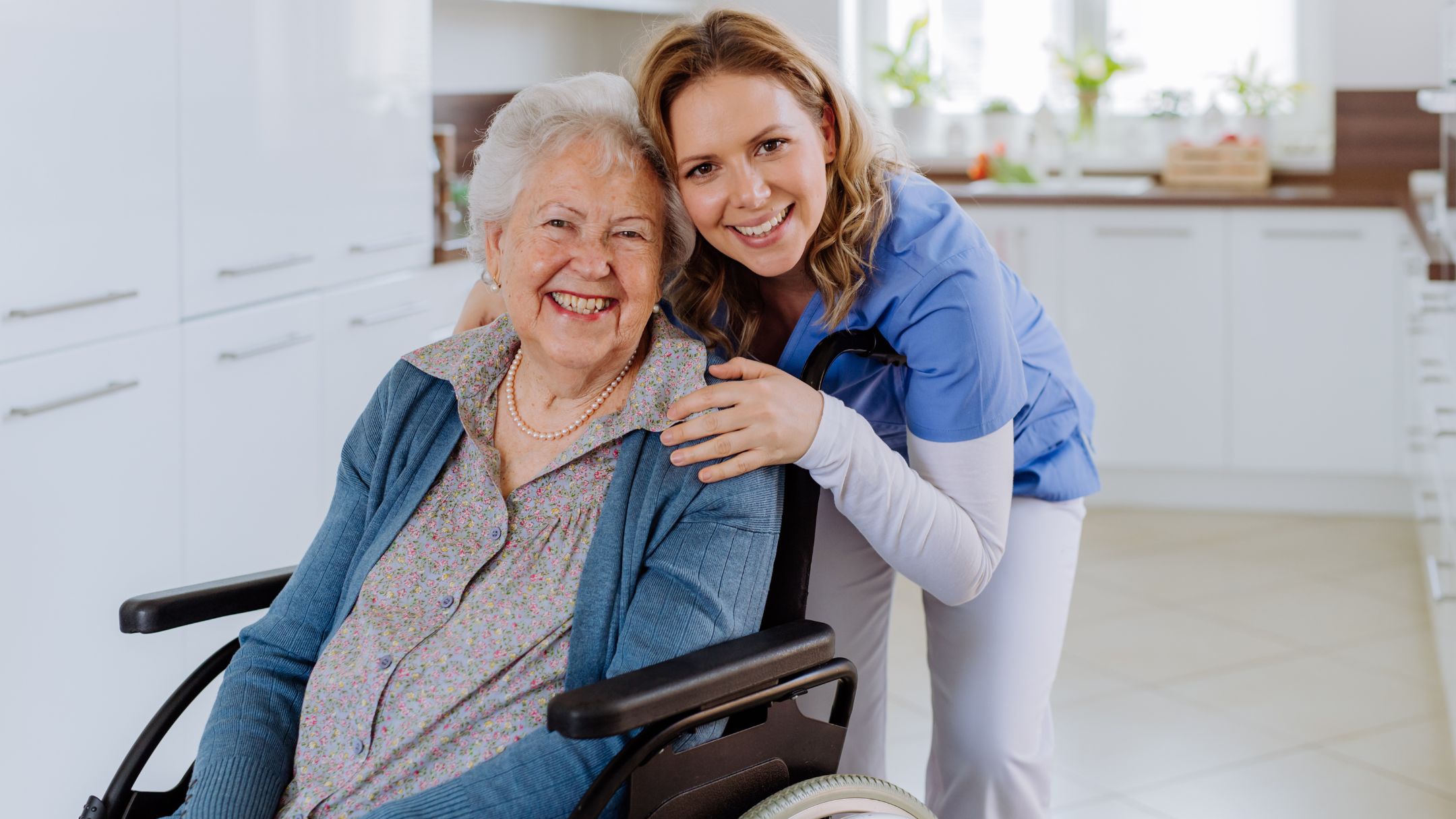 Smiling nurse with elderly woman in wheelchair at home