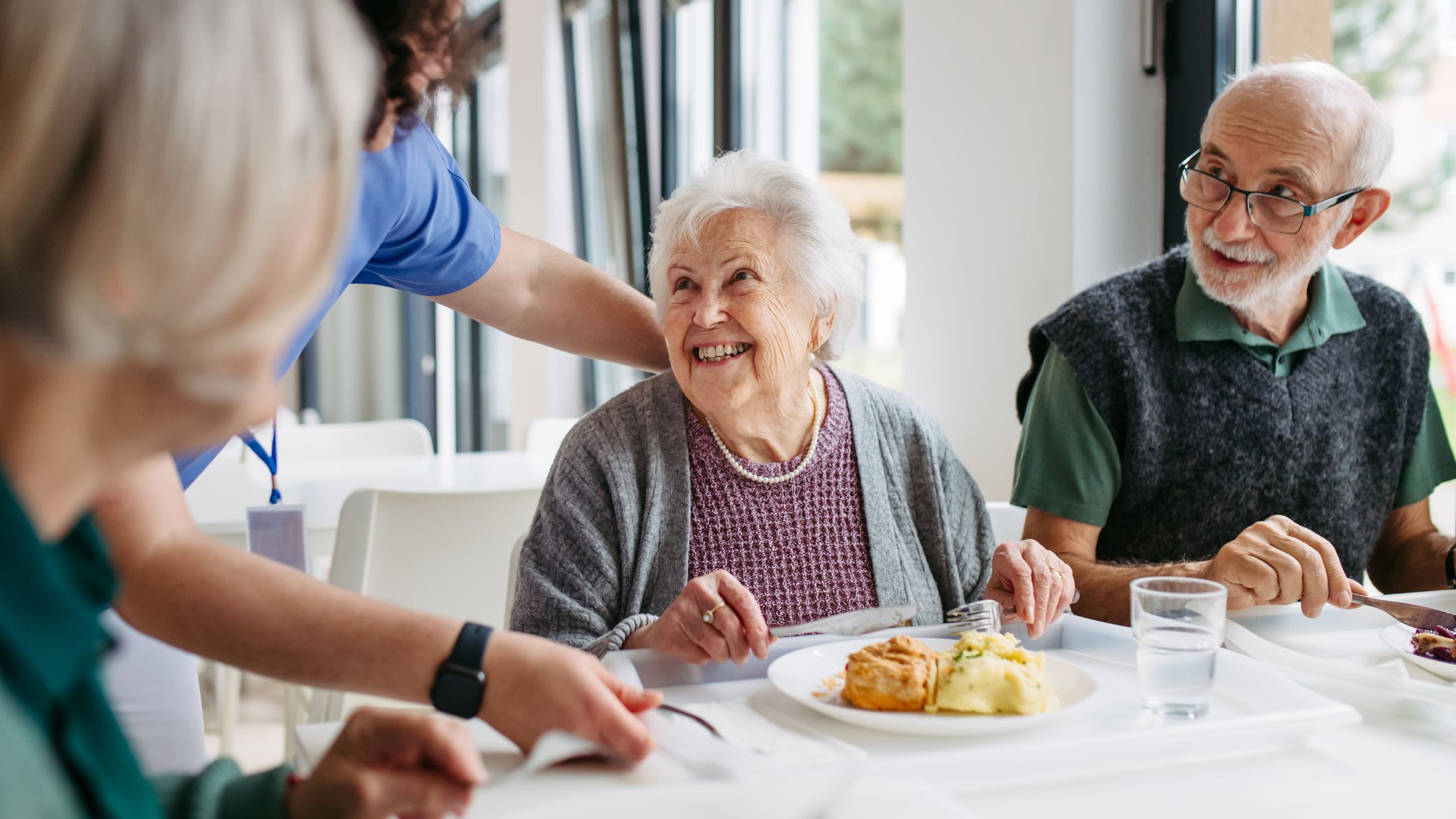 Seniors enjoying a meal together with a caregiver